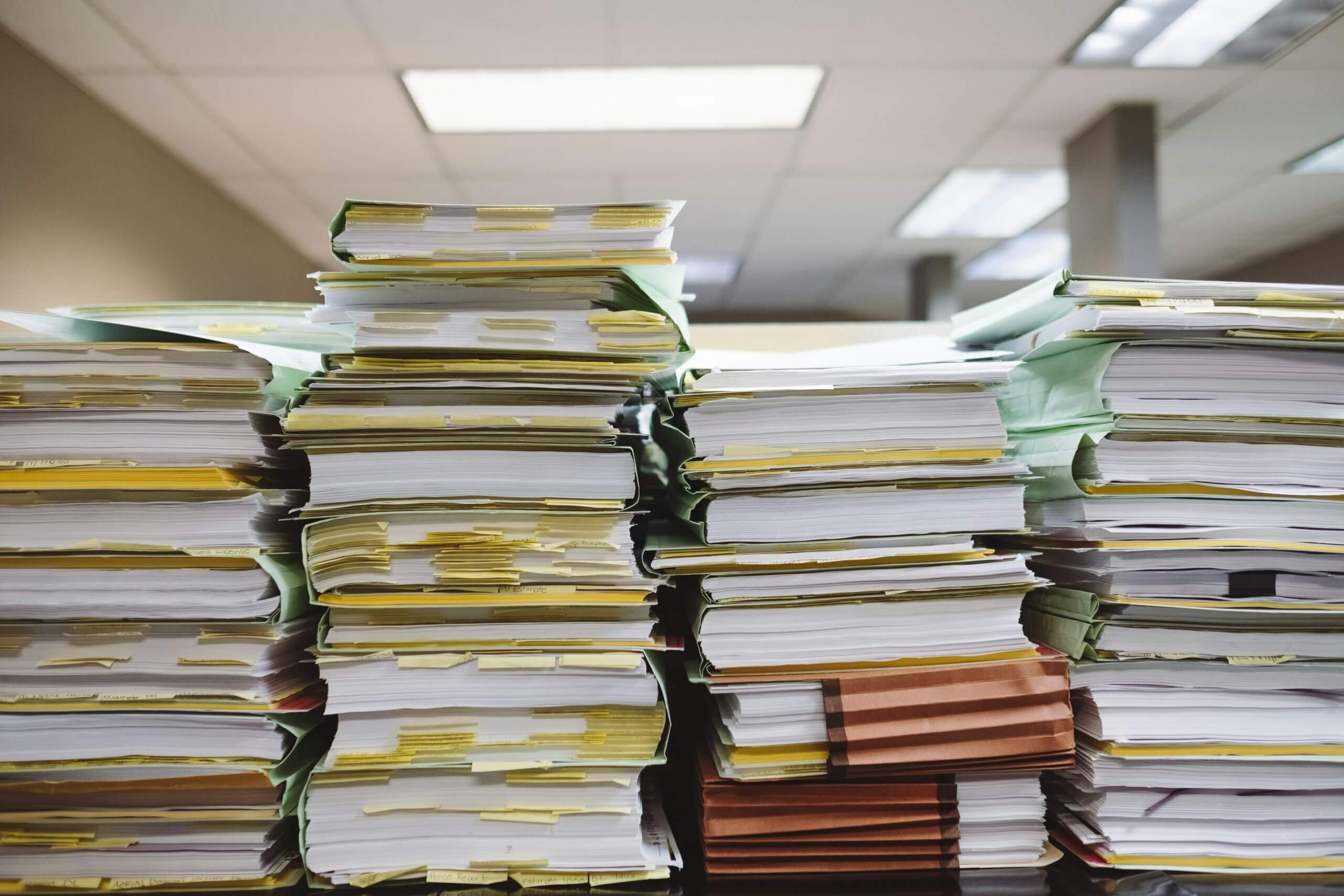 Stacks of documents and files piled high on a desk.