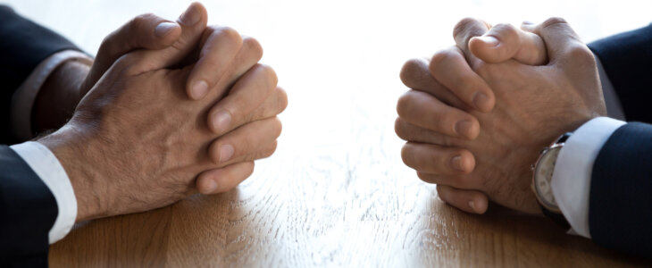 Clasped hands of two business men negotiators opponents opposite on table as politicians dialogue debate, applicant hr job interview, negotiating competitors, rivals confrontation challenge concept
