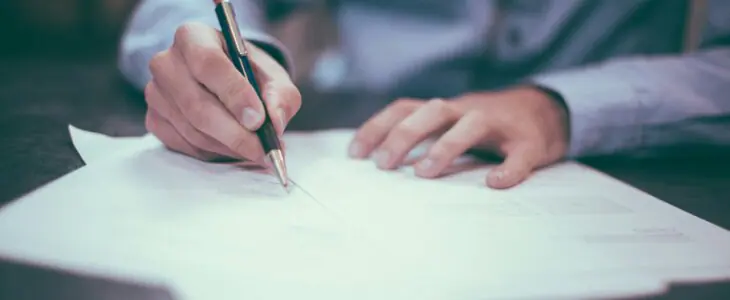 Close-up of hands writing on legal papers with a pen