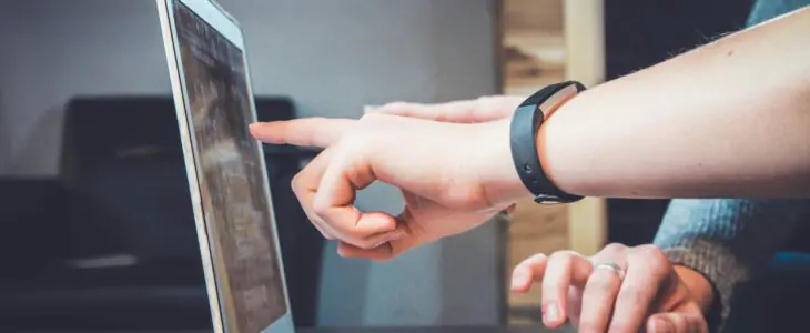 Hands pointing at a laptop screen during a discussion.