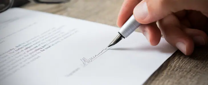 Close up of hand of businessman signing a form. Business man signing contract for future deal. Business man signing legal document. Male hand signing employee contract with a bond.